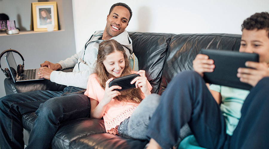 father happily watching kids playing handled game